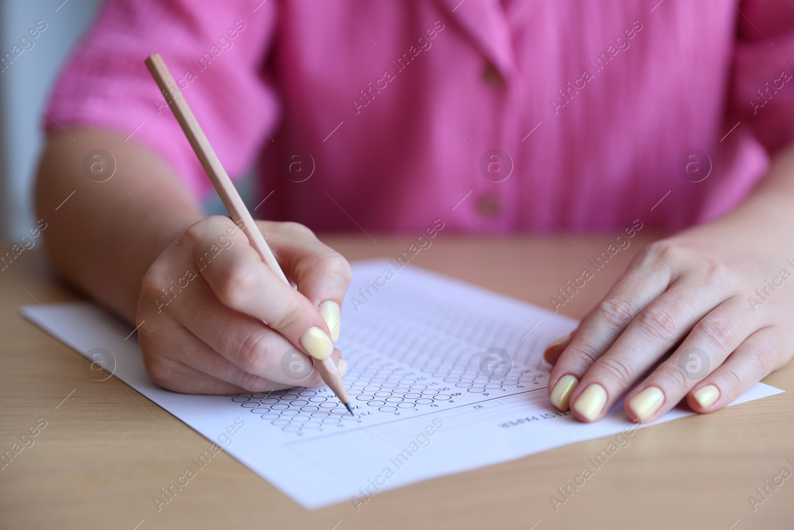 Student filling out multiple choice test at wooden table, closeup. Passing exam Photo of Student filling out multiple choice test at wooden table, closeup. Passing exam