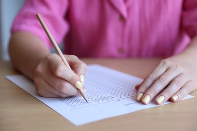Photo of Student filling out multiple choice test at wooden table, closeup. Passing exam