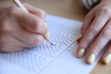 Photo of Student filling out multiple choice test at table, closeup. Passing exam