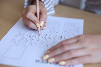 Photo of Student filling out multiple choice test at table, closeup. Passing exam