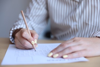 Photo of Student filling out multiple choice test at table in class, closeup. Passing exam