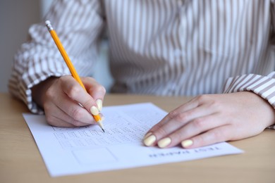 Photo of Student filling out multiple choice test at table, closeup. Passing exam