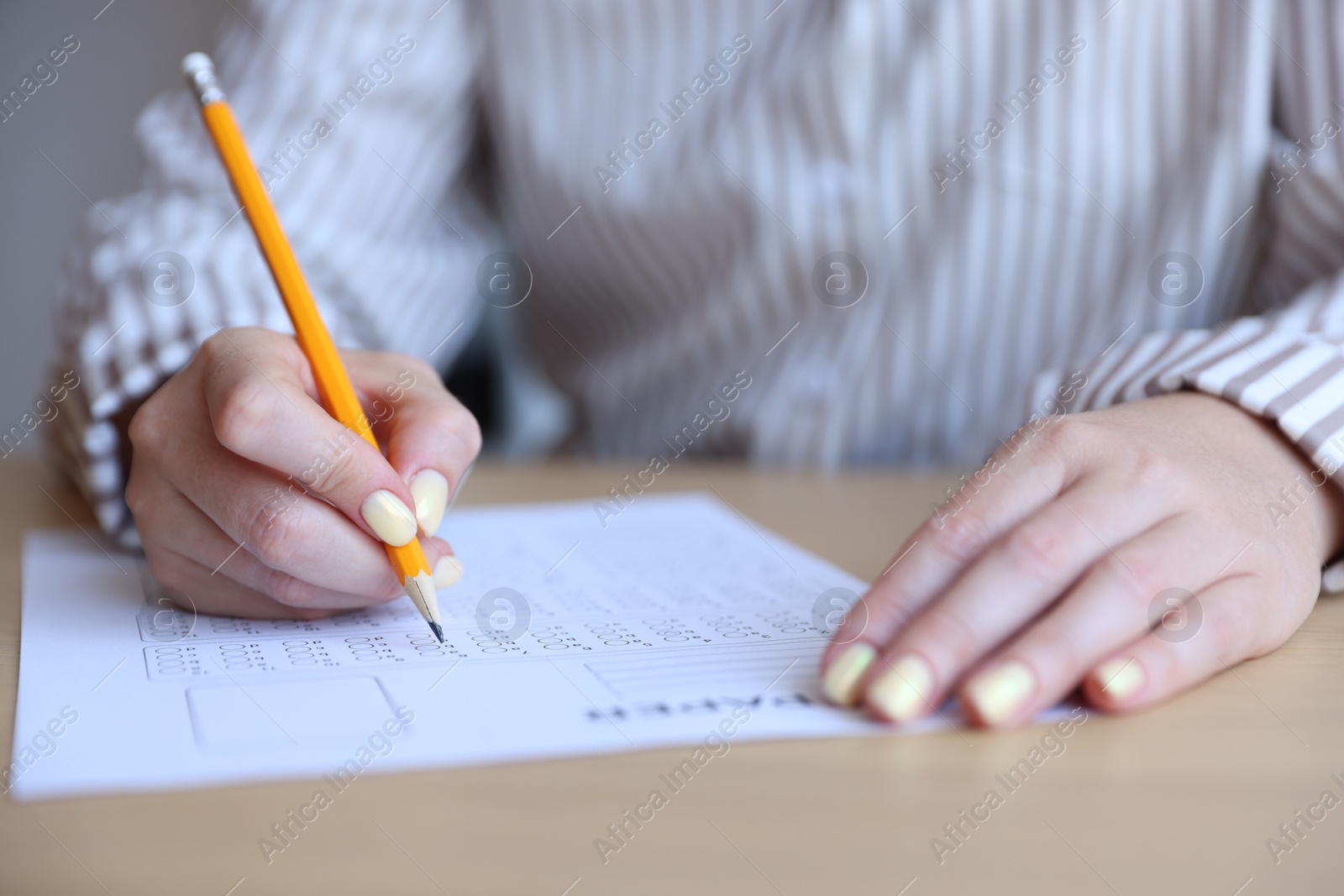 Student filling out multiple choice test at table, closeup. Passing exam Photo of Student filling out multiple choice test at table, closeup. Passing exam