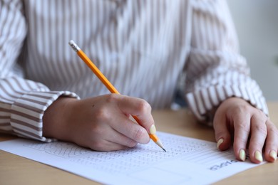 Photo of Student filling out multiple choice test at table in class, closeup. Passing exam