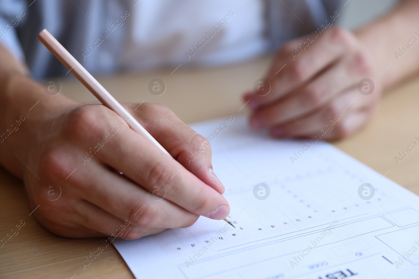 Student filling out multiple choice test at wooden table, closeup. Passing exam Photo of Student filling out multiple choice test at wooden table, closeup. Passing exam