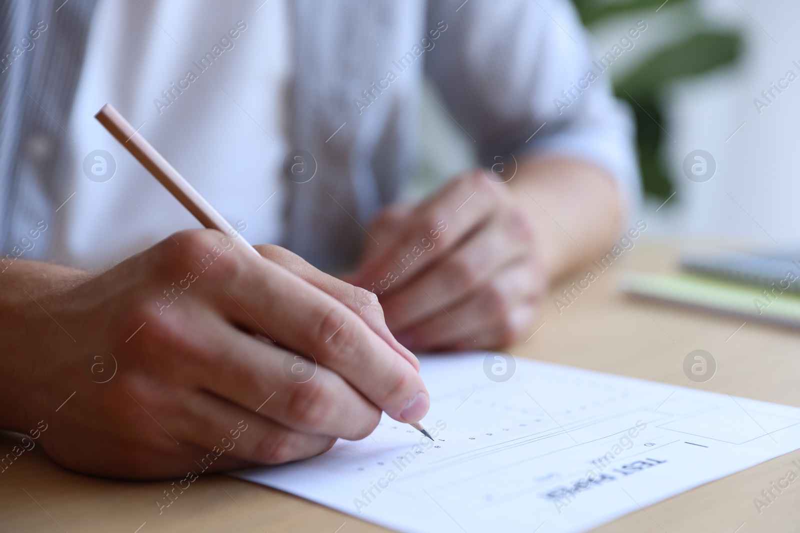 Student filling out multiple choice test at table in class, closeup. Passing exam Photo of Student filling out multiple choice test at table in class, closeup. Passing exam