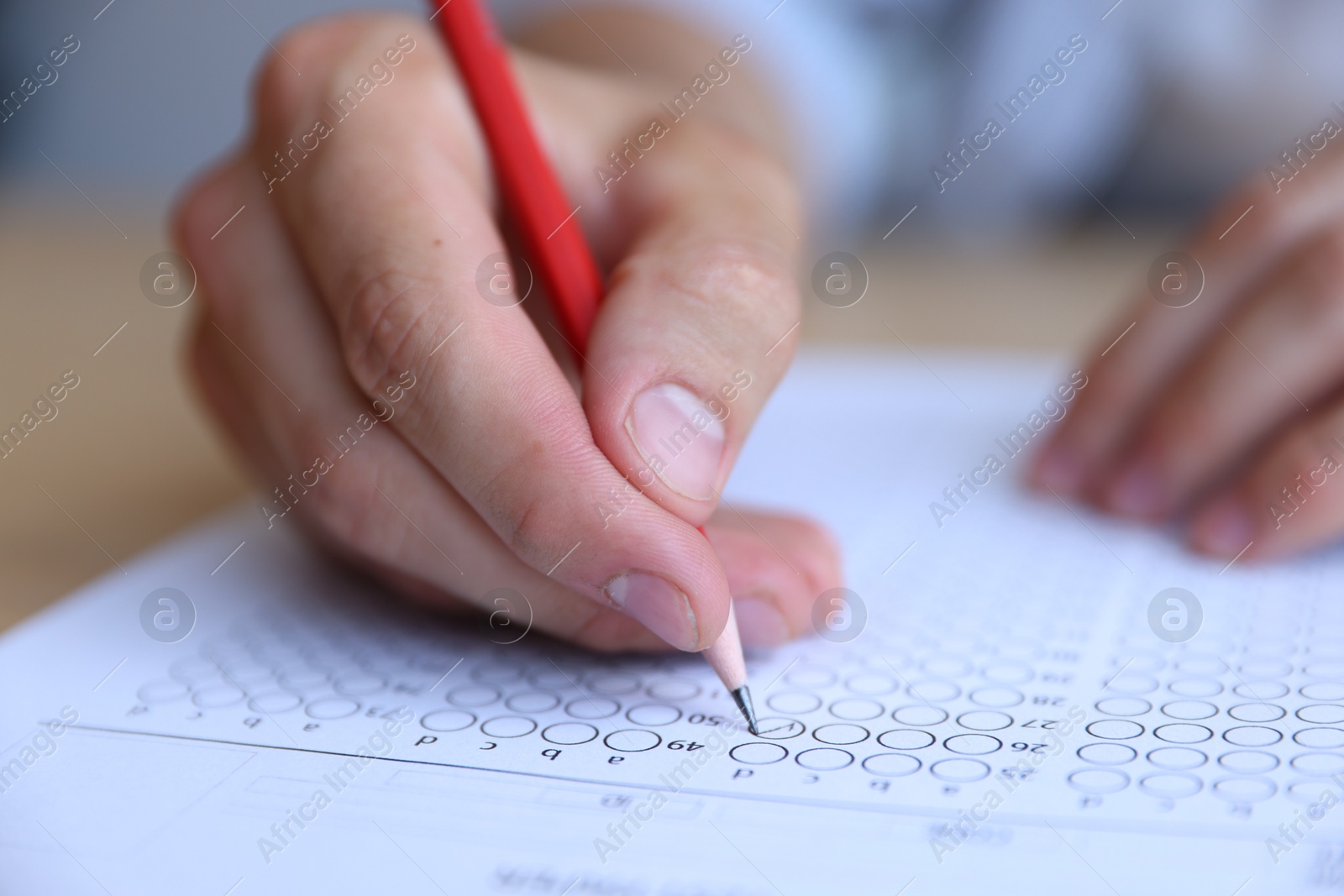 Student filling out multiple choice test at table, closeup. Passing exam Photo of Student filling out multiple choice test at table, closeup. Passing exam