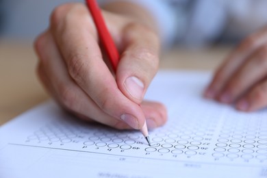 Photo of Student filling out multiple choice test at table, closeup. Passing exam