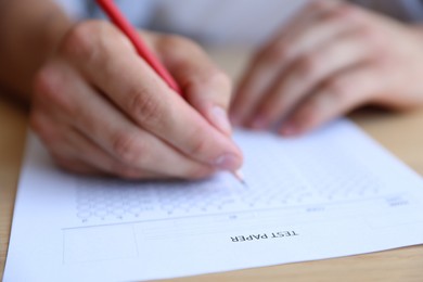 Photo of Student filling out multiple choice test at table, closeup. Passing exam
