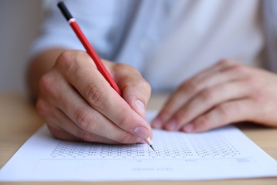 Photo of Student filling out multiple choice test at table, closeup. Passing exam