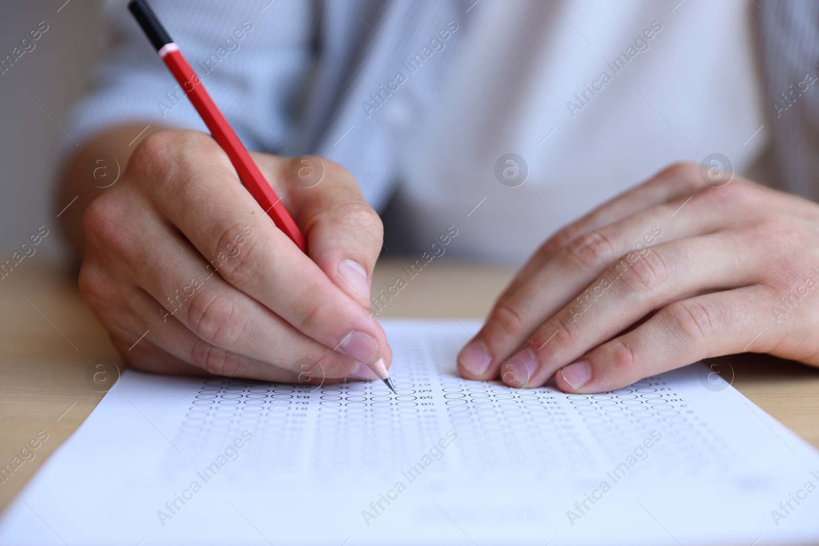 Student filling out multiple choice test at table, closeup. Passing exam Photo of Student filling out multiple choice test at table, closeup. Passing exam