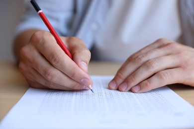 Photo of Student filling out multiple choice test at table, closeup. Passing exam