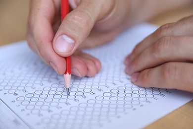 Photo of Student filling out multiple choice test at table, closeup. Passing exam