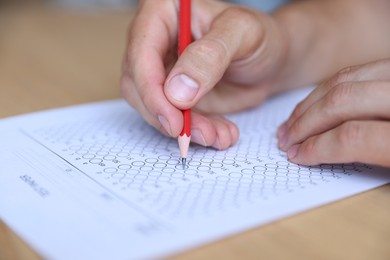 Photo of Student filling out multiple choice test at table, closeup. Passing exam