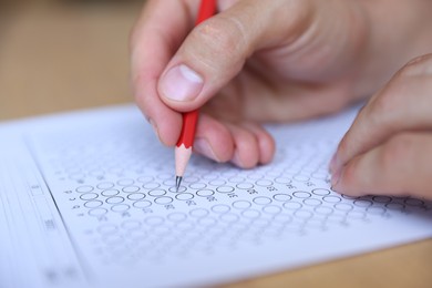 Photo of Student filling out multiple choice test at table, closeup. Passing exam