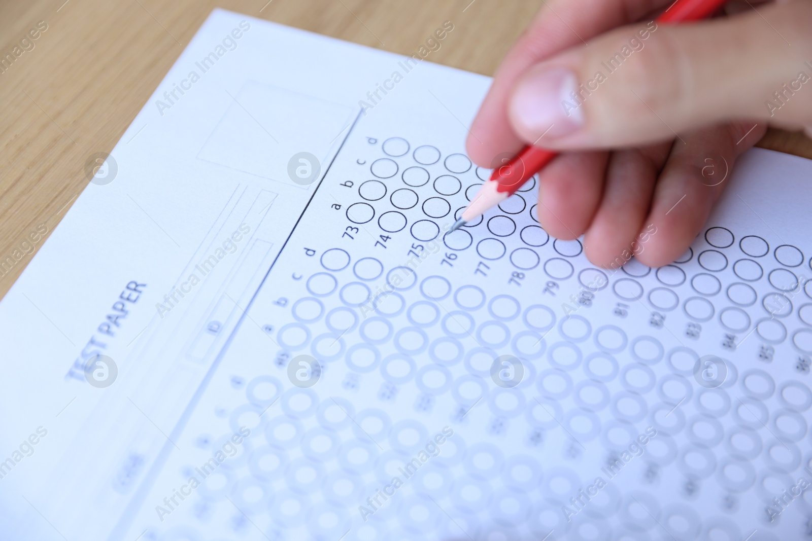 Student filling out multiple choice test at wooden table, closeup. Passing exam Photo of Student filling out multiple choice test at wooden table, closeup. Passing exam