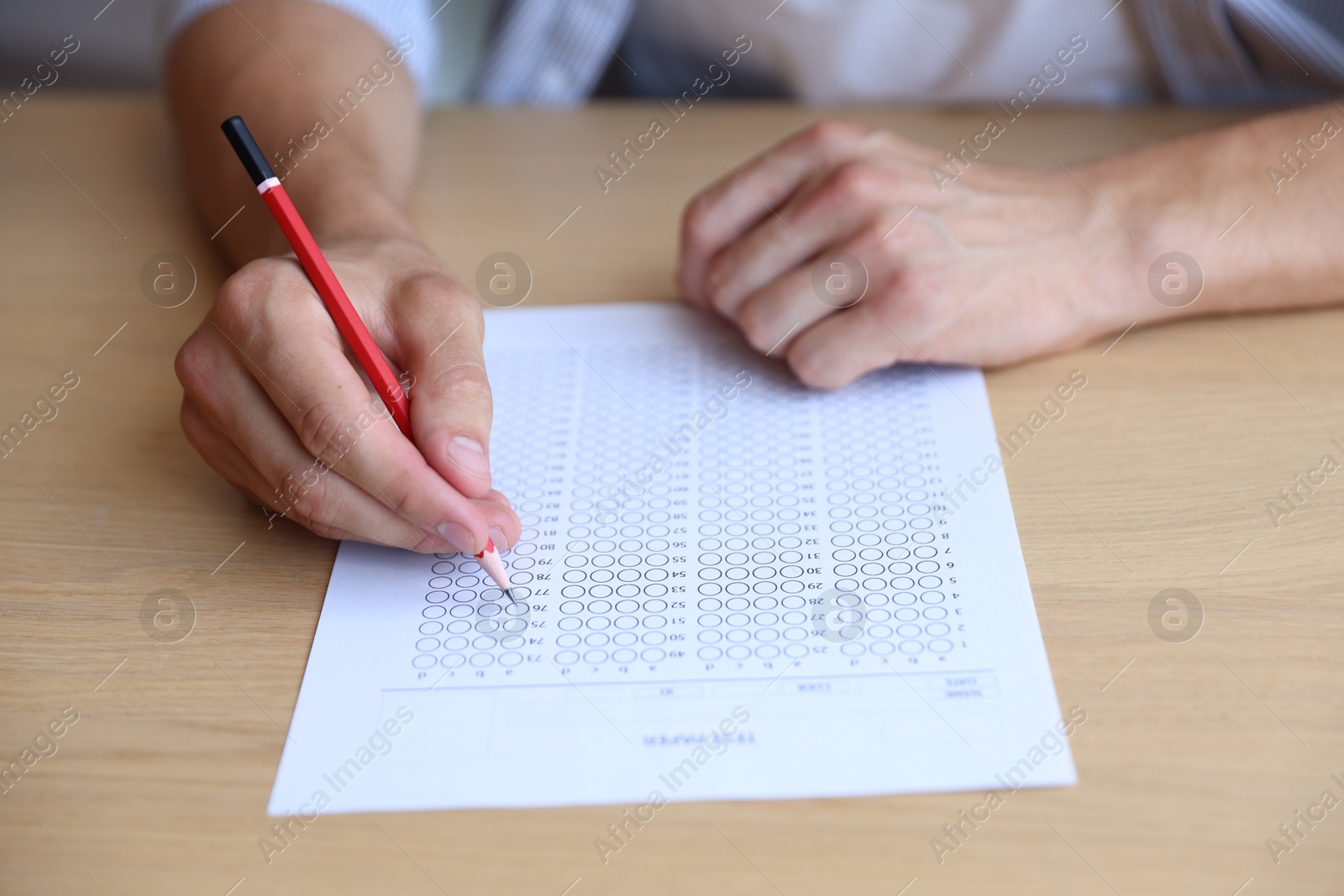 Student filling out multiple choice test at wooden table, closeup. Passing exam Photo of Student filling out multiple choice test at wooden table, closeup. Passing exam