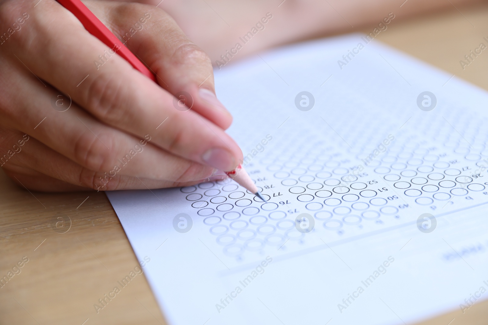 Student filling out multiple choice test at wooden table, closeup. Passing exam Photo of Student filling out multiple choice test at wooden table, closeup. Passing exam