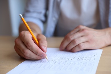 Photo of Student filling out multiple choice test at table in class, closeup. Passing exam