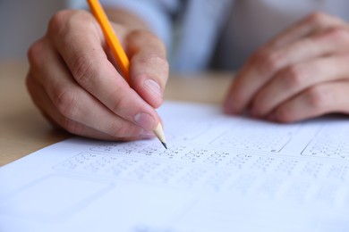 Photo of Student filling out multiple choice test at table, closeup. Passing exam