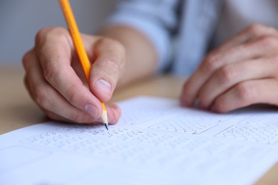 Photo of Student filling out multiple choice test at table in class, closeup. Passing exam