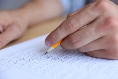 Photo of Student filling out multiple choice test at table, closeup. Passing exam