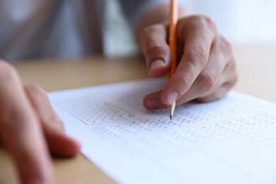 Photo of Student filling out multiple choice test at table, closeup. Passing exam