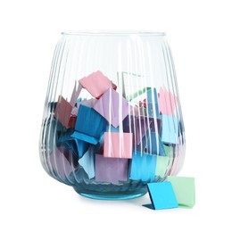 Photo of Many colorful paper pieces in glass isolated on white