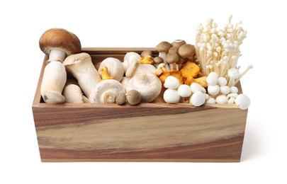 Photo of Different raw mushrooms in wooden crate isolated on white