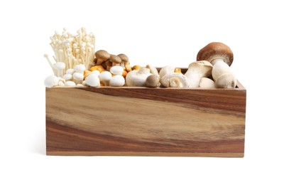 Photo of Different raw mushrooms in wooden crate isolated on white