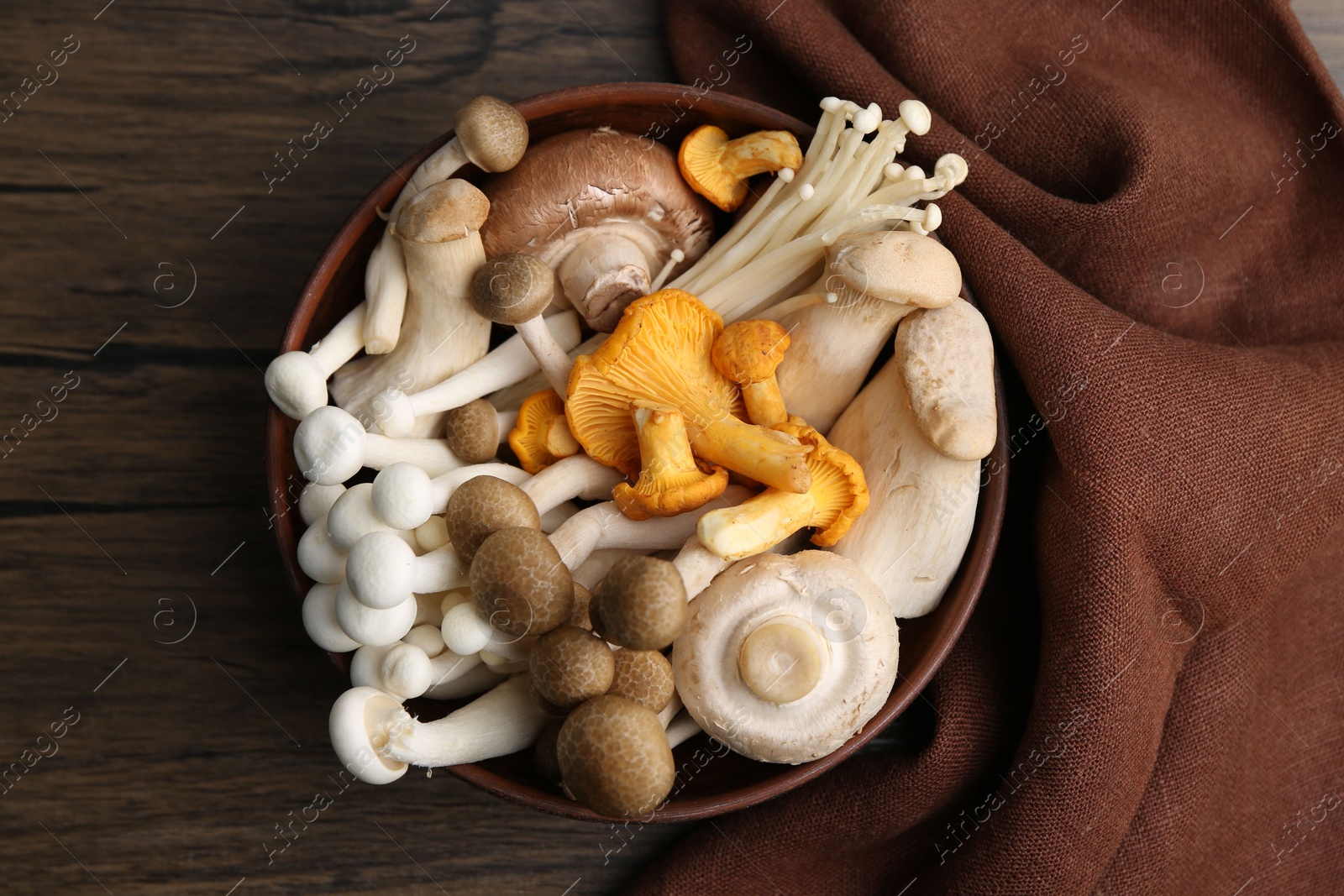 Different raw mushrooms in bowl on wooden table, top view Photo of Different raw mushrooms in bowl on wooden table, top view
