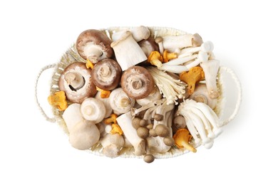 Photo of Different raw mushrooms in wicker basket isolated on white, top view