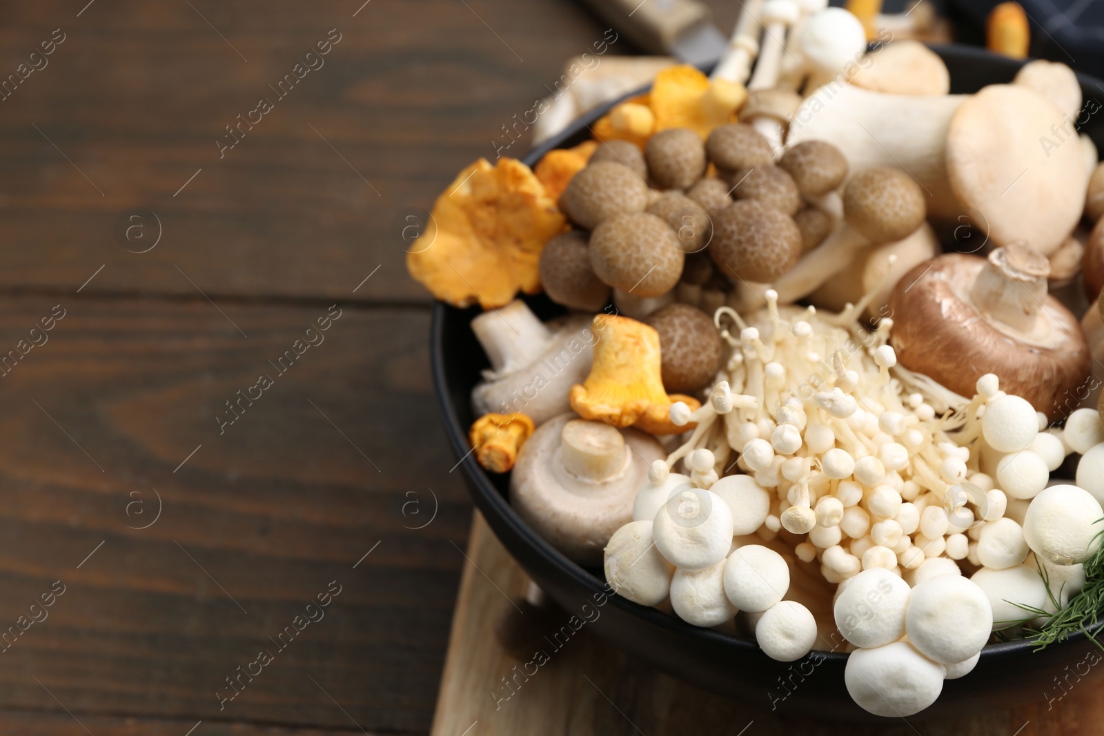 Different raw mushrooms in bowl on wooden table, closeup. Space for text Photo of Different raw mushrooms in bowl on wooden table, closeup. Space for text