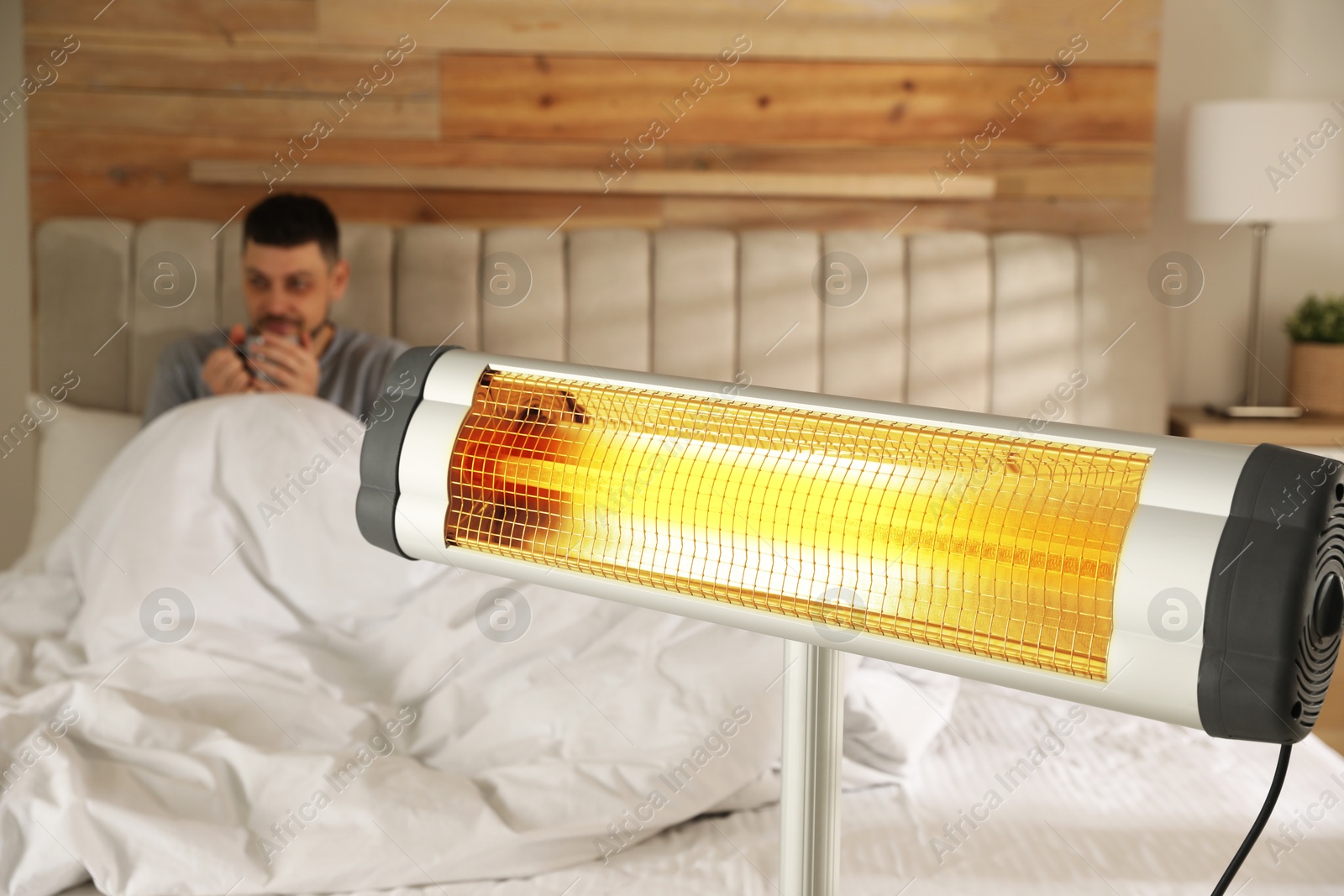Man in room with electric heater, selective focus Image of Man in room with electric heater, selective focus
