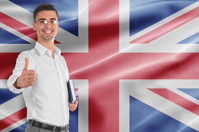 Image of Teacher with book showing thumbs-up against flag of United Kingdom. Language school
