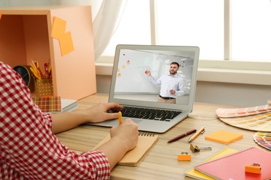 Image of E-learning concept. Student having online video chat with teacher via laptop at desk, closeup