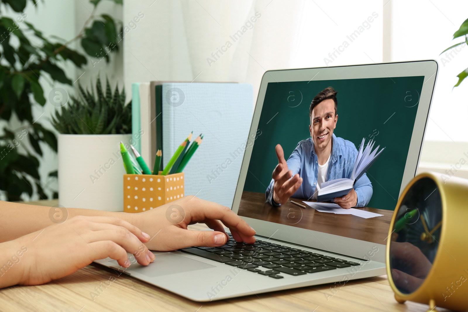 Image of E-learning concept. Student having online video chat with teacher via laptop at desk, closeup