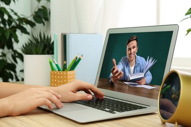 Image of E-learning concept. Student having online video chat with teacher via laptop at desk, closeup