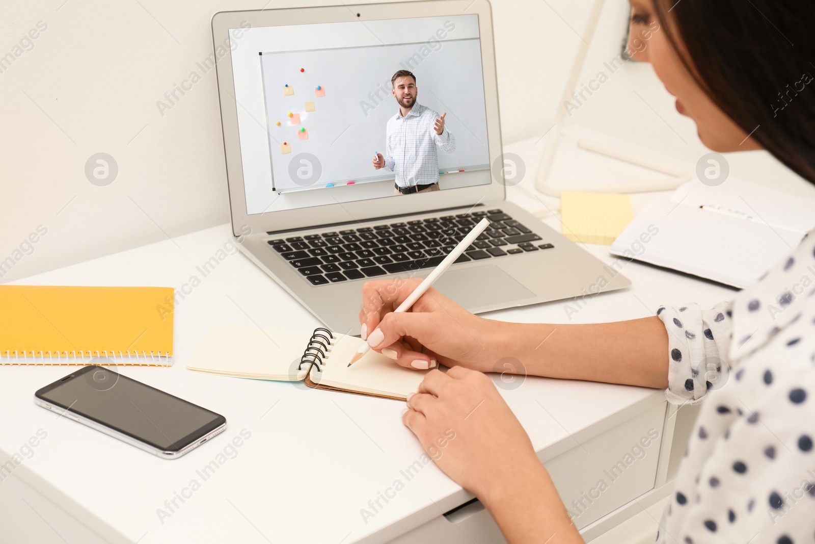 Image of E-learning concept. Student having online video chat with teacher via laptop at desk, closeup