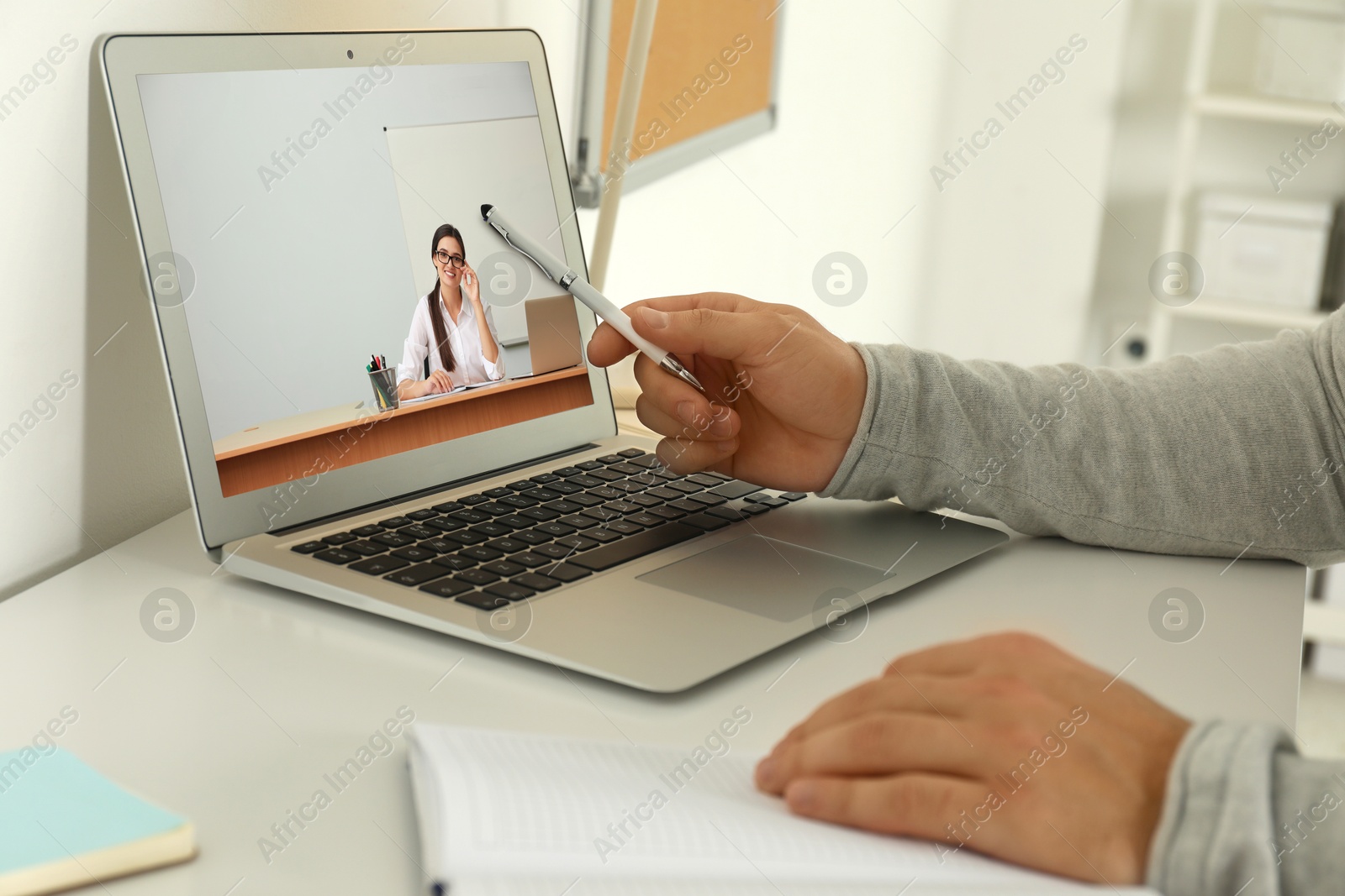 Image of E-learning concept. Student having online video chat with teacher via laptop at desk, closeup