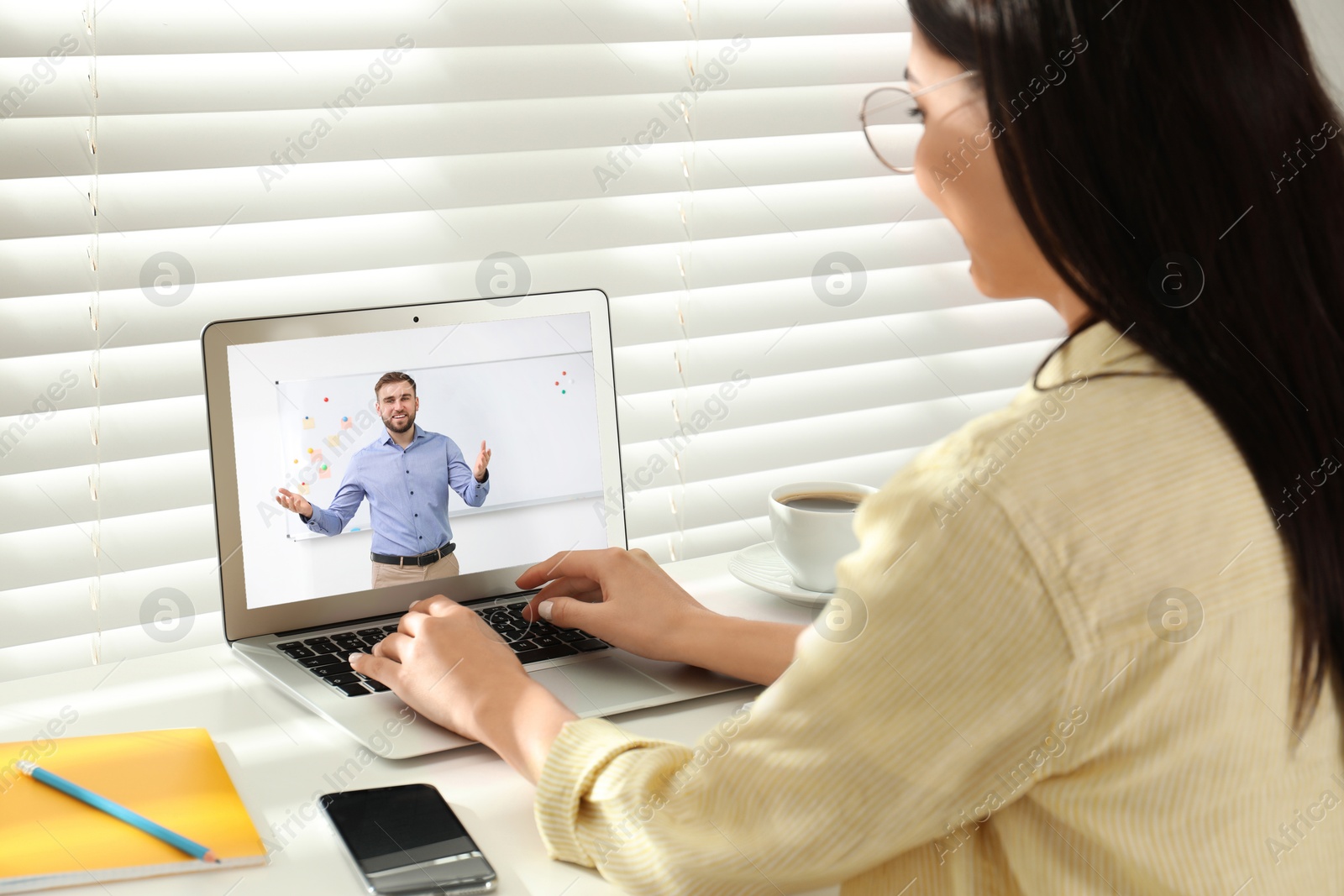 Image of E-learning concept. Student having online video chat with teacher via laptop at desk