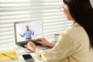 Image of E-learning concept. Student having online video chat with teacher via laptop at desk