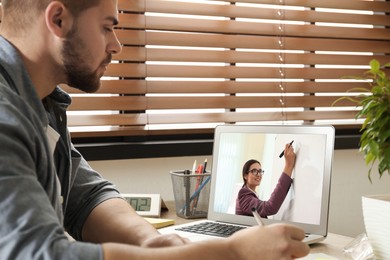 Image of E-learning concept. Student having online video chat with teacher via laptop at desk
