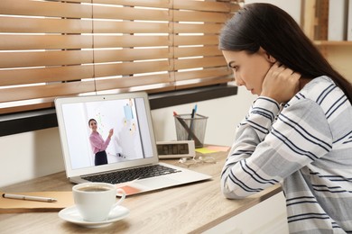 Image of E-learning concept. Student having online video chat with teacher via laptop at desk