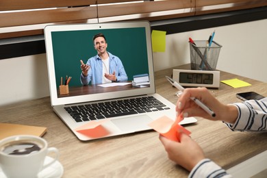 Image of E-learning concept. Student having online video chat with teacher via laptop at desk, closeup