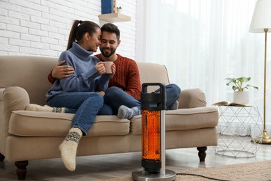 Image of Couple on sofa in room with electric heater