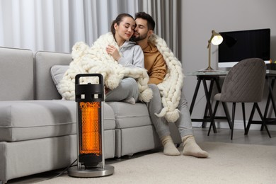 Image of Couple on sofa in room with electric heater