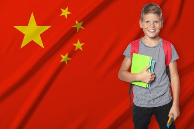 Image of Little boy with backpack and stationery against flag of China. Language school