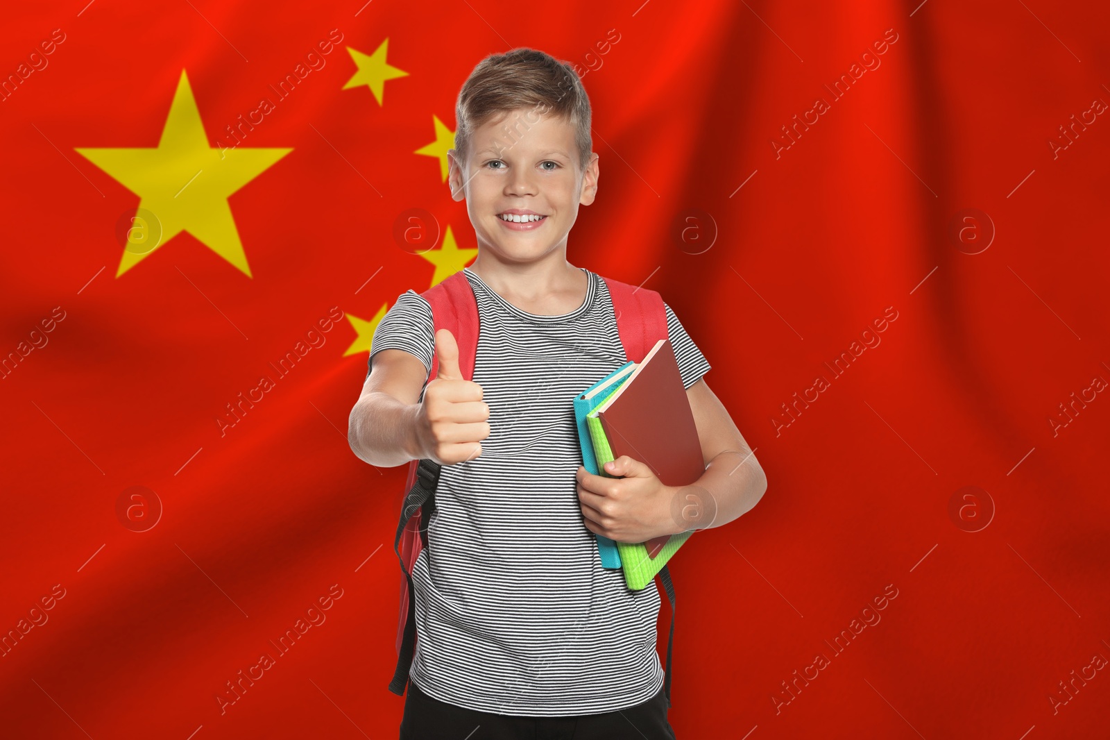 Little boy with backpack and notebooks showing thumbs-up against flag of China. Language school Image of Little boy with backpack and notebooks showing thumbs-up against flag of China. Language school
