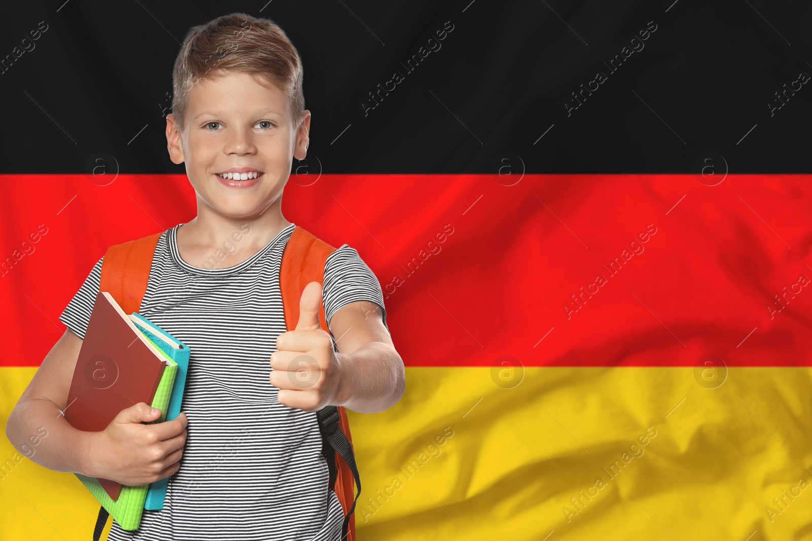Little boy with backpack and notebooks showing thumbs-up against flag of Germany. Language school Image of Little boy with backpack and notebooks showing thumbs-up against flag of Germany. Language school
